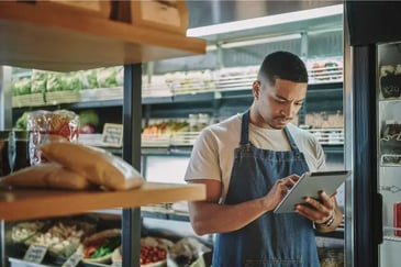 Male grocery retailer doing stock inventory on tablet