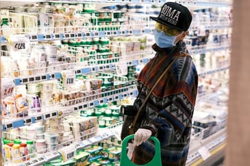 Person wearing a mask standing in the grocery store dairy aisle