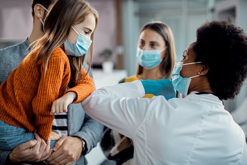 Child with parents elbow bumping with doctor with masks