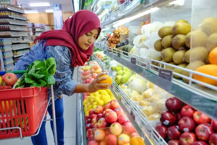Muslim woman grabbing an orange in the produce aisle
