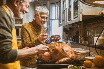 Older female and male couple glaze cooked Thanksgiving turkey