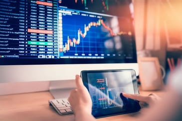 charts on a computer and tablet indicating profitability