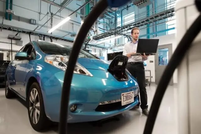 Electric car at the mechanic with man looking at laptop