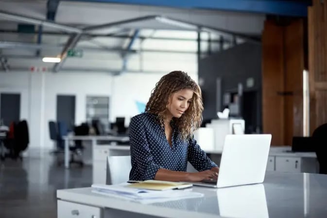 Female office worker using laptop at desk