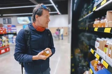 Man in workout gear picking out a juice in grocery store