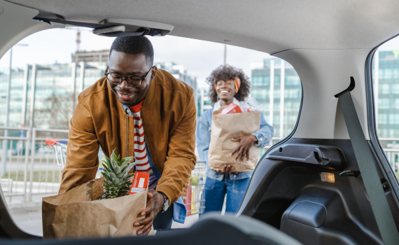 Male and female couple placing groceries in the trunk of their car