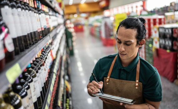 Male grocery employee doing stock inventory with a tablet