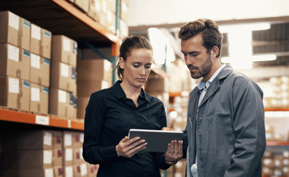 Male and female merchant doing stock inventory in warehouse using tablet