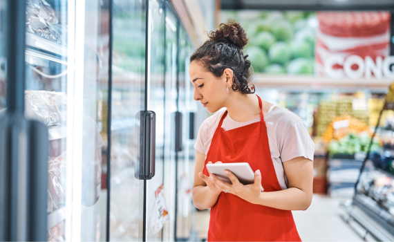 Female grocery employee checking stock with tablet