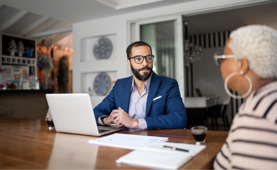 Male insurer using laptop while meeting with elderly female client