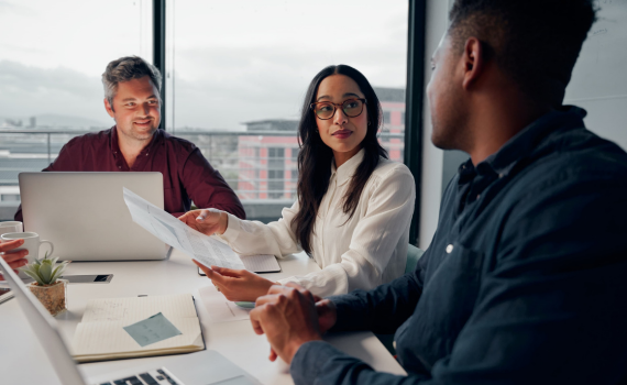 Male and female insurers working on laptops while discussing in office