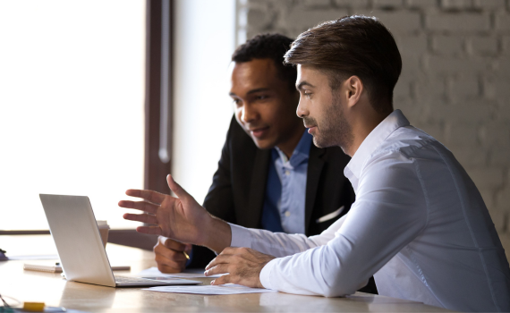 Male insurers collaborating and using laptop