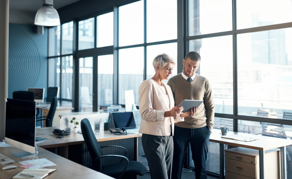 Male and female insurer collaborating and looking at tablet