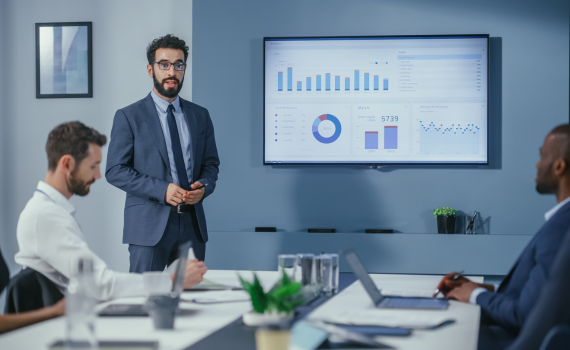 Male insurer presenting on company finances to male work colleagues