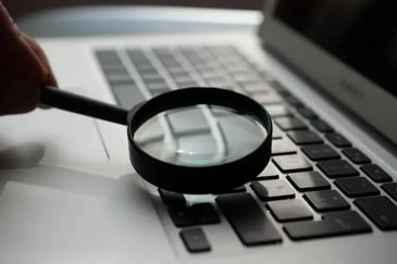 Magnifying lens being held over a laptop keyboard