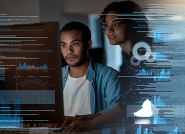 Colleagues writing code on a computer in AI tech office