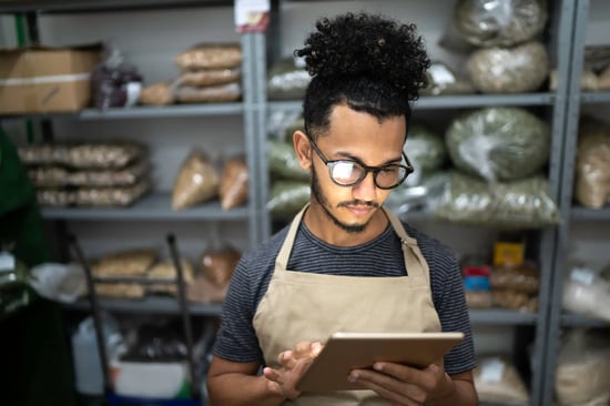 male grocery employee doing stock inventory in store room using tablet