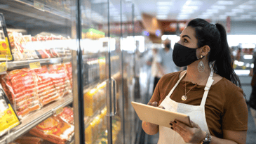 Female grocery employee doing stock inventory in the meat aisle