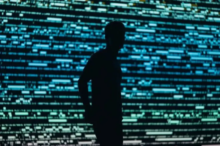 Silhouette of a man in front of a large computer screen 