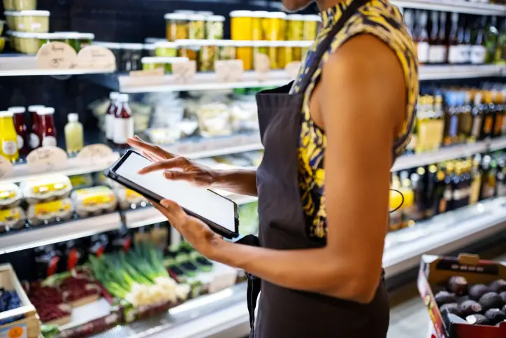 Female grocery employee using tablet in fresh aisle