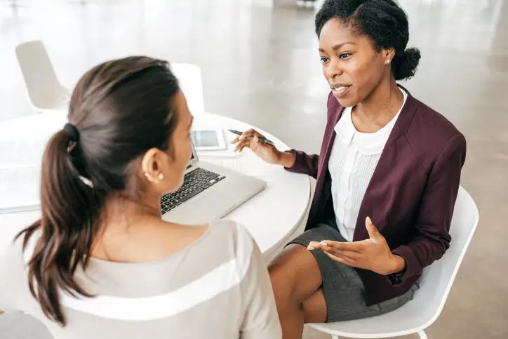 Female insurer assisting a client while using a laptop