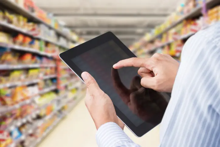 Male grocery merchant using tablet in grocery aisle