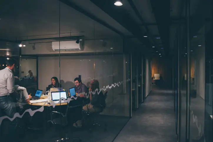 Employees meeting in a boardroom with computers open and working together