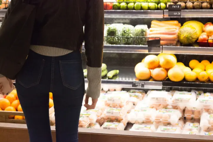 Lady standing in front of fresh food in grocery shop deciding on what to get