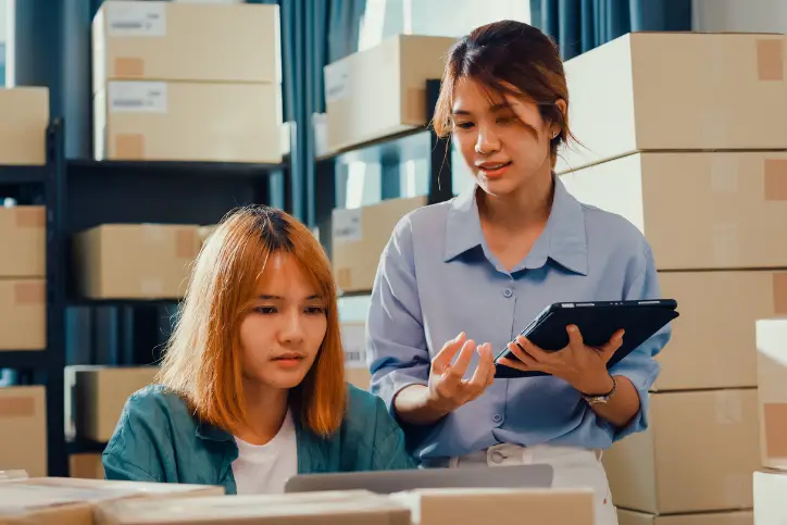 Female merchants doing stock inventory in warehouse using tablets