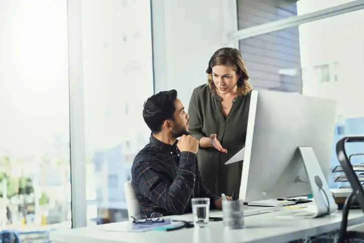 Female and male insurer having a conversation and looking at a desktop computer