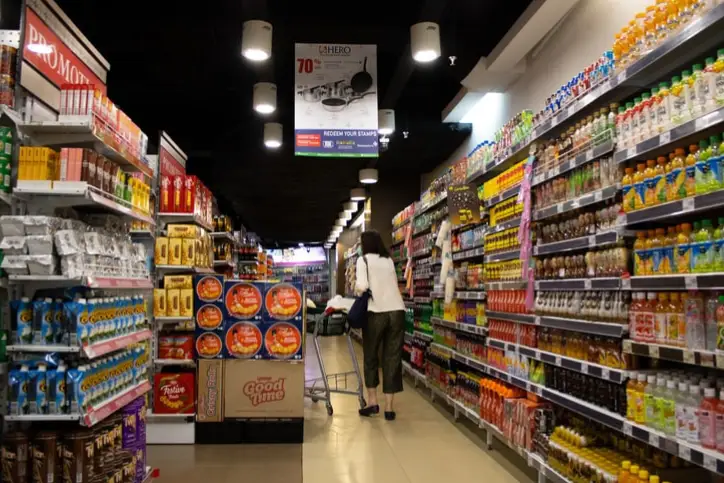 Lady walking down a grocery store aisle and showing a lot of products