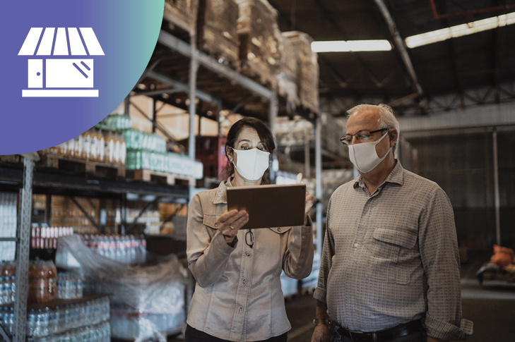 two coworkers in a warehouse looking at a tablet