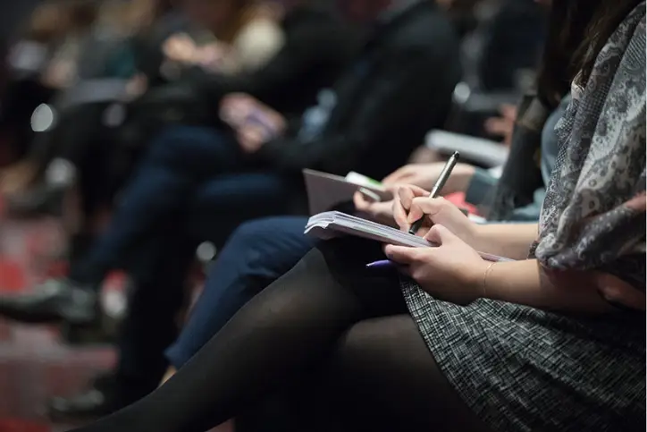 Audience members writing notes in notebooks