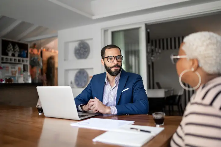 Male insurer helping a client with a laptop