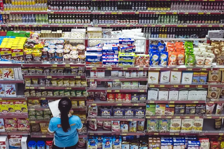 Retail grocery employee doing stock inventory in a grocery aisle