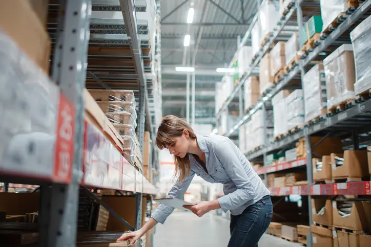 Female merchant checking inventory in warehouse with tablet