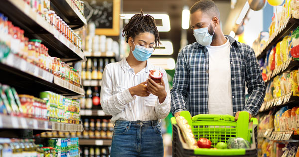 couple with masks shopping in a grocery shop aisle
