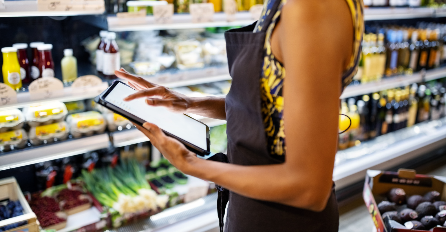 Female grocery employee using tablet in fresh aisle