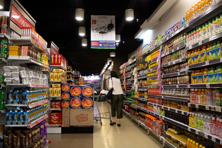 Lady walking down a grocery store aisle and showing a lot of products